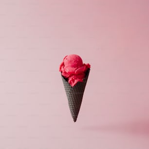 Strawberry ice cream in black cone on pink pastel background. Summer creative concept.