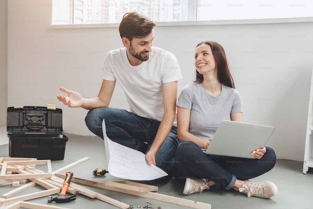 Young man and woman doing apartment repair together using laptop