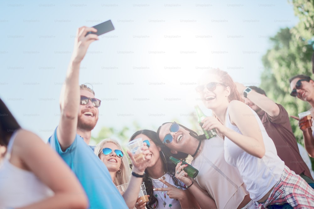 Amigos tomando selfie en la fiesta al aire libre, luz del sol en el fondo