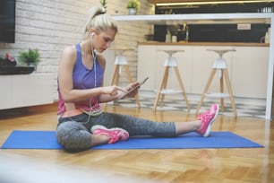 Young woman workout at home. Woman using digital tablet. Listening music on smart phone..