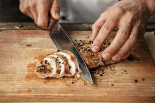 Mature male professional chef cooking meal indoors cutting meat