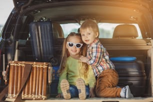 Viaja en coche familia juntos hermano y hermana sentados en un maletero
