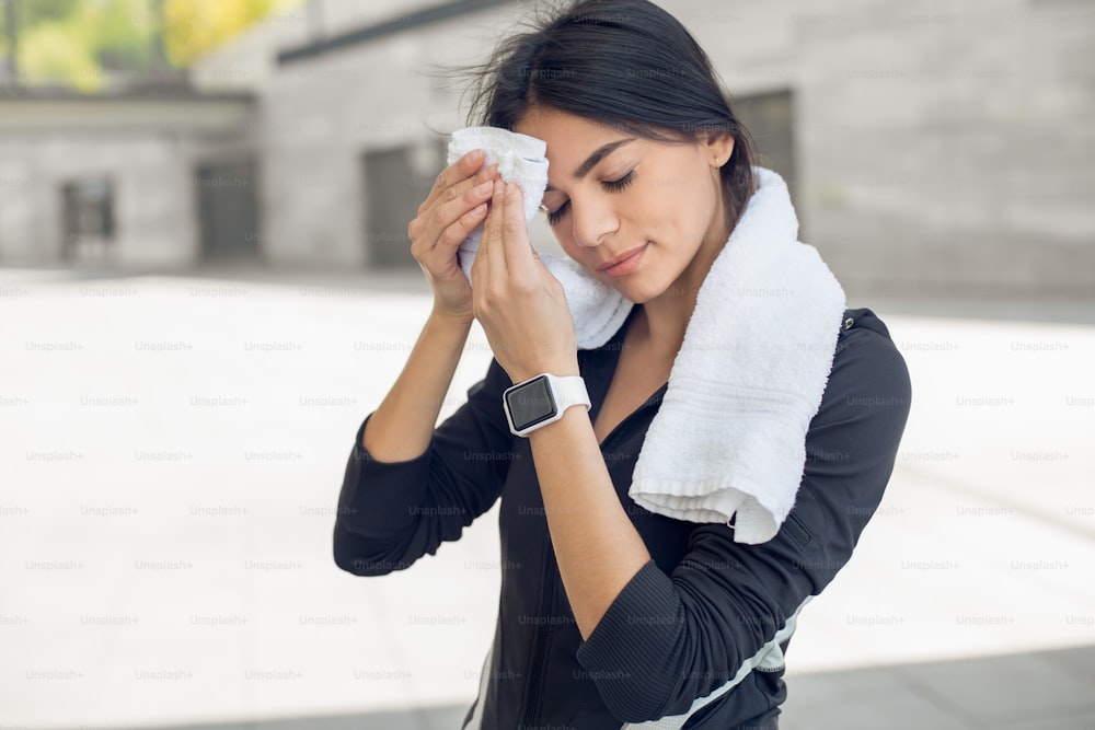 Young female active exercise workout on street outside holding towel