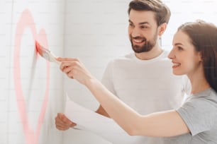 Young man and woman doing apartment repair together paint walls