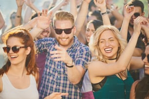 Group of people dancing at summer festival, hands raised