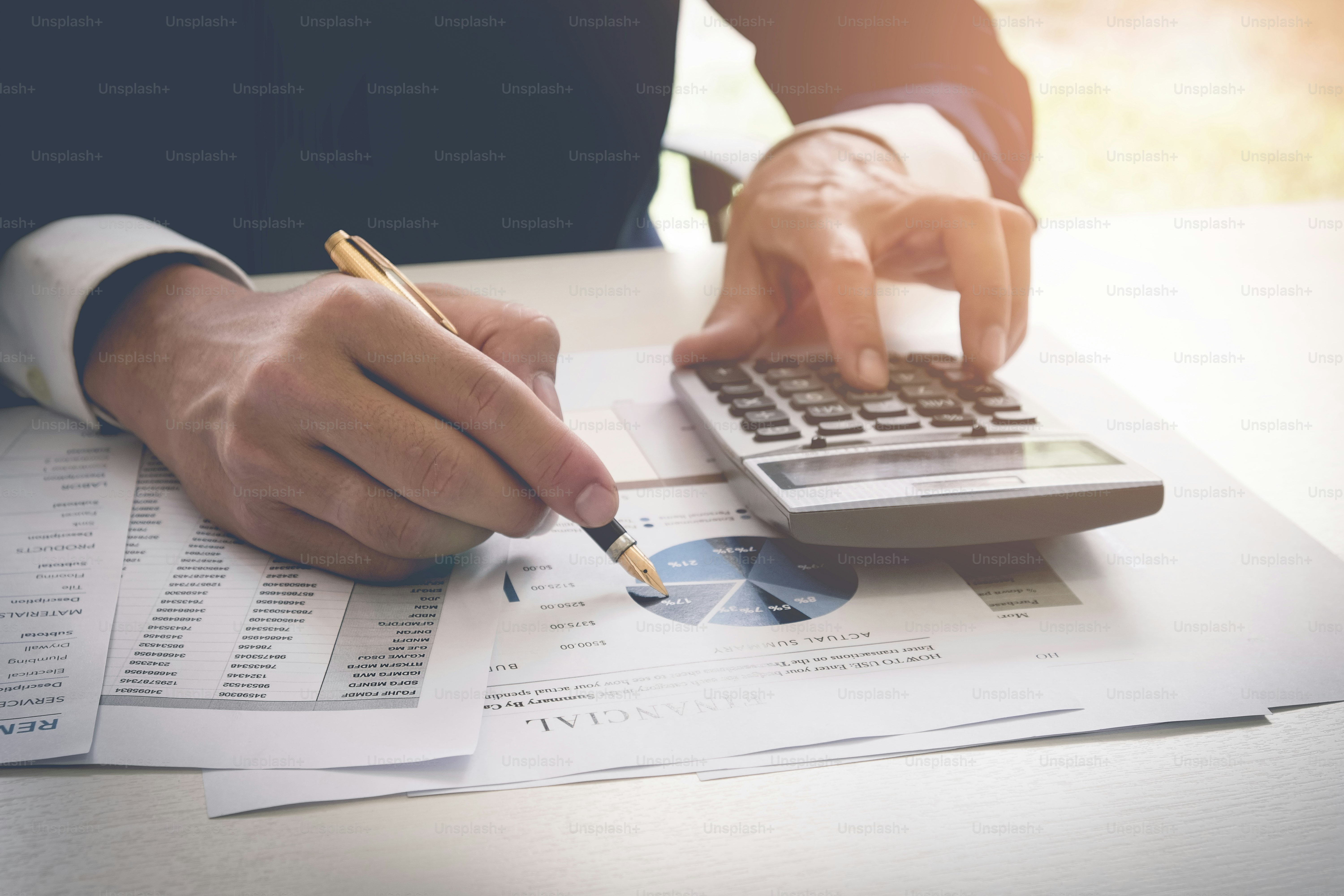 Businessman pen pointing graph chart while using a calculator to calculate the numbers. Accounting , Accountancy, Calculation Concept. vintage filter effect
