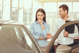 Young man and woman in a car rental service signing contract