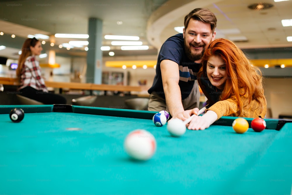 Happy couple playing snooker and billiards at club