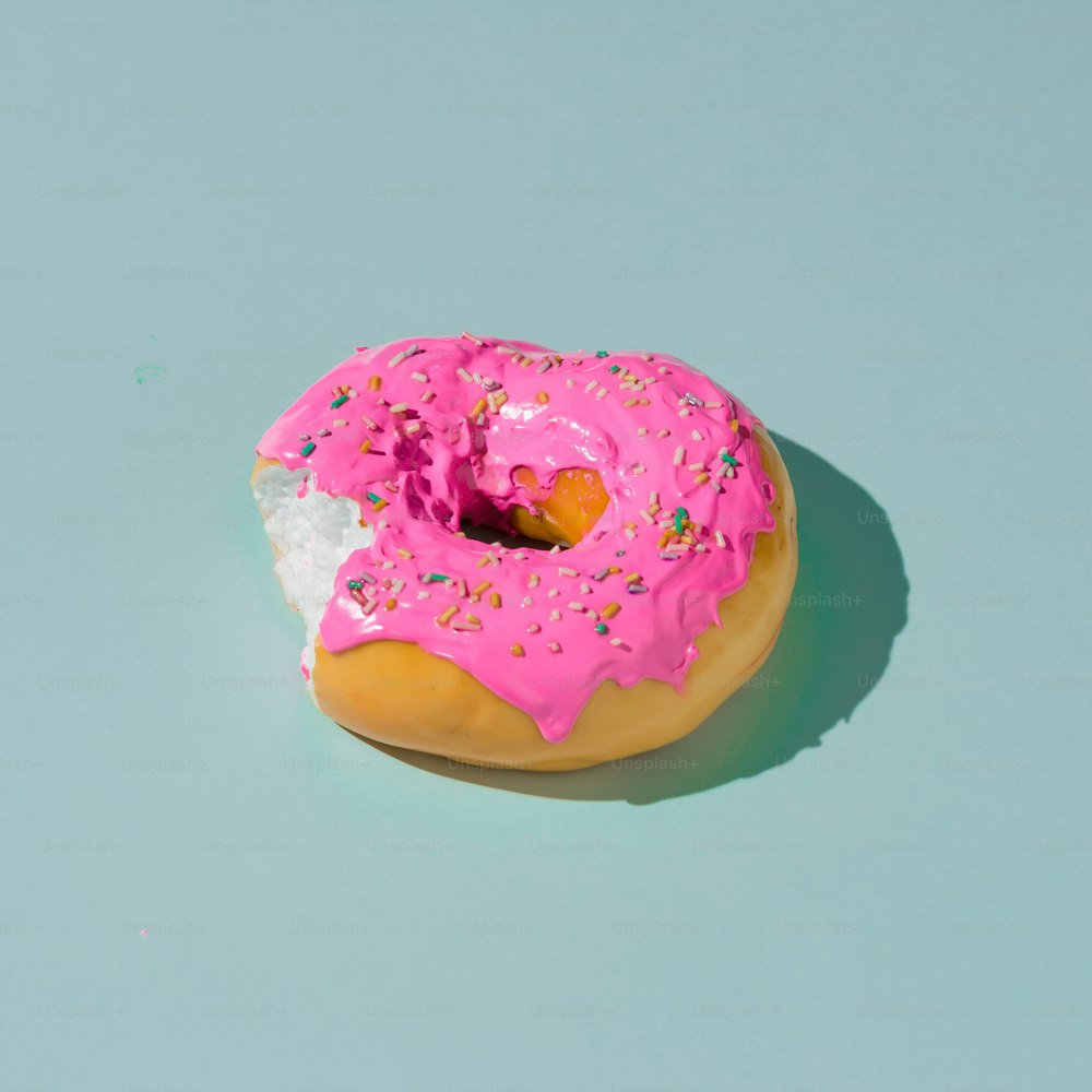 Pink glazed donut on blue pastel background. Creative concept.