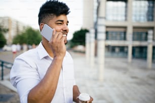 Young handsome Afro American man standing in front of huge modern business building smiling and talking on cell phone.