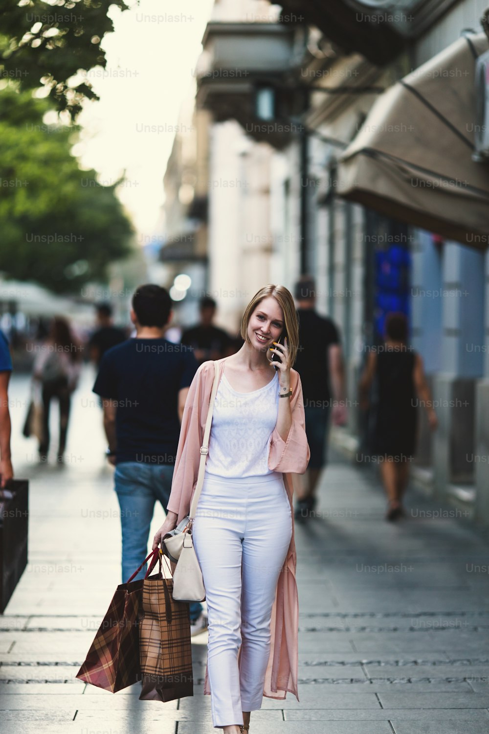 Schöne und modische junge Frau mit Einkaufstaschen, die auf der Stadtstraße steht und auf die Ladenfront schaut