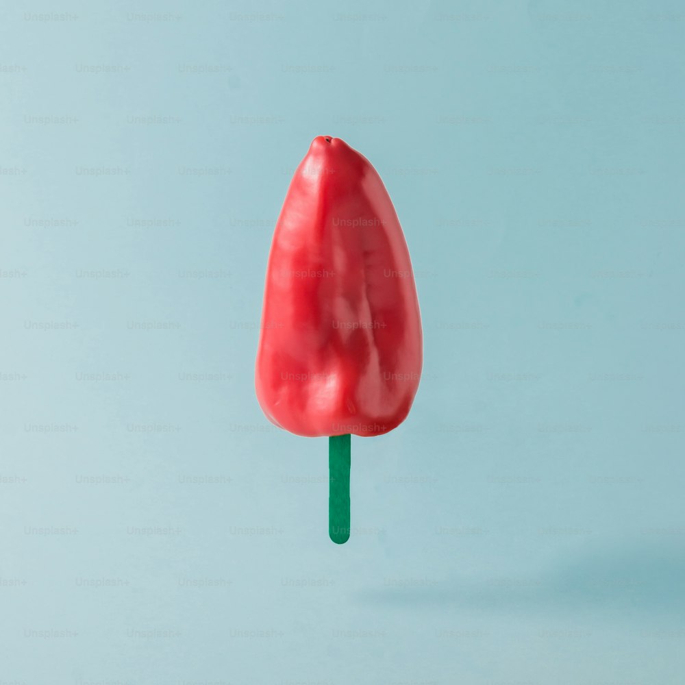 Roter Pfeffer mit Eisstange auf pastellblauem Hintergrund. Kreatives Food-Konzept.