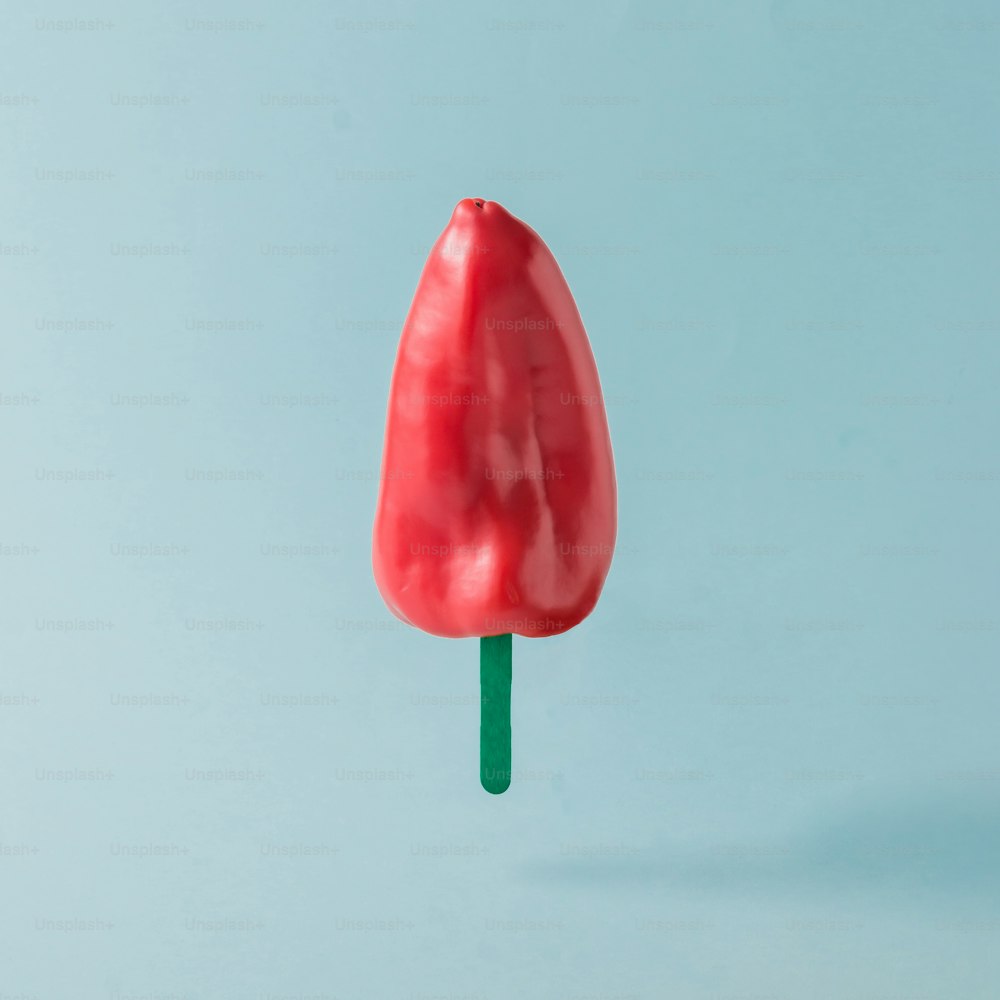 Red pepper with ice cream stick on pastel blue background. Food creative concept.