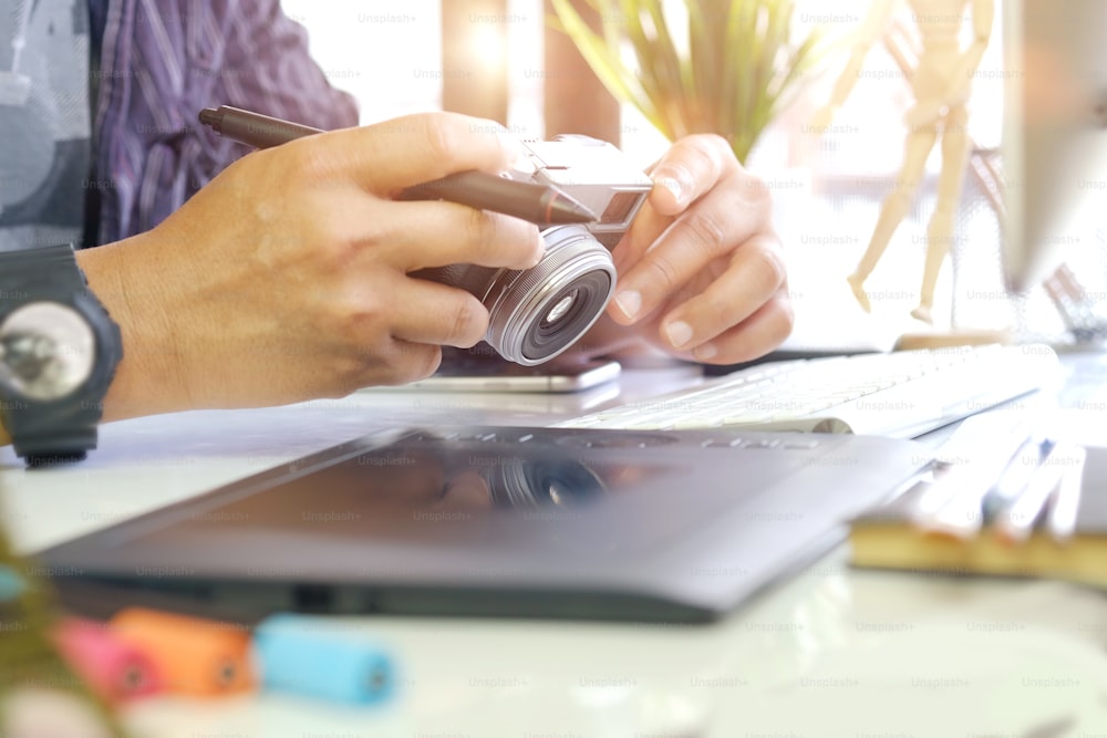 Young hipster graphic designer man using digital graphic tablet while working at modern office, professional male retoucher sitting at modern workspace with wooden table, generic design tablet