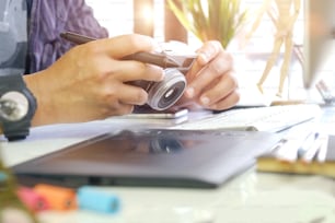 Young hipster graphic designer man using digital graphic tablet while working at modern office, professional male retoucher sitting at modern workspace with wooden table, generic design tablet