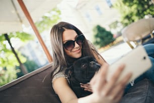 Bella ragazza adolescente seduta nel ristorante del caffè con il suo adorabile cucciolo di bulldog francese. Tema persone e cani.