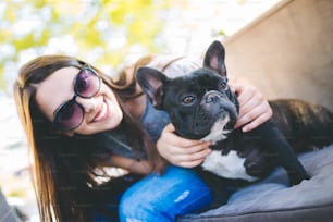 Beautiful teenage girl sitting in cafe restaurant with her adorable French bulldog puppy. People and dogs theme.