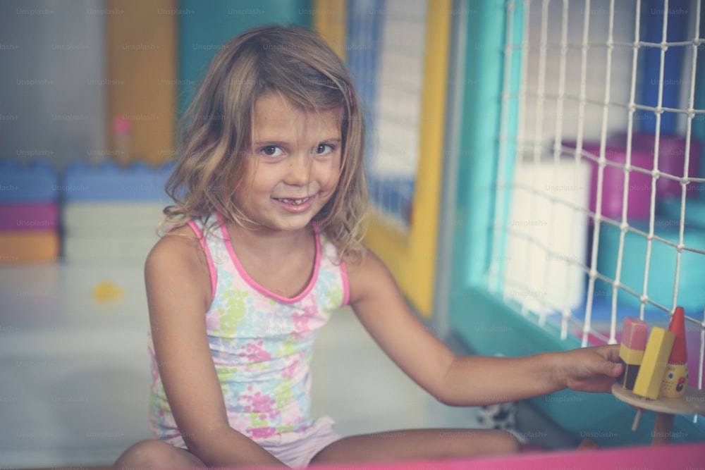 Petite fille dans l’aire de jeux. Fille caucasienne jouant avec un jouet. Regarder la caméra.