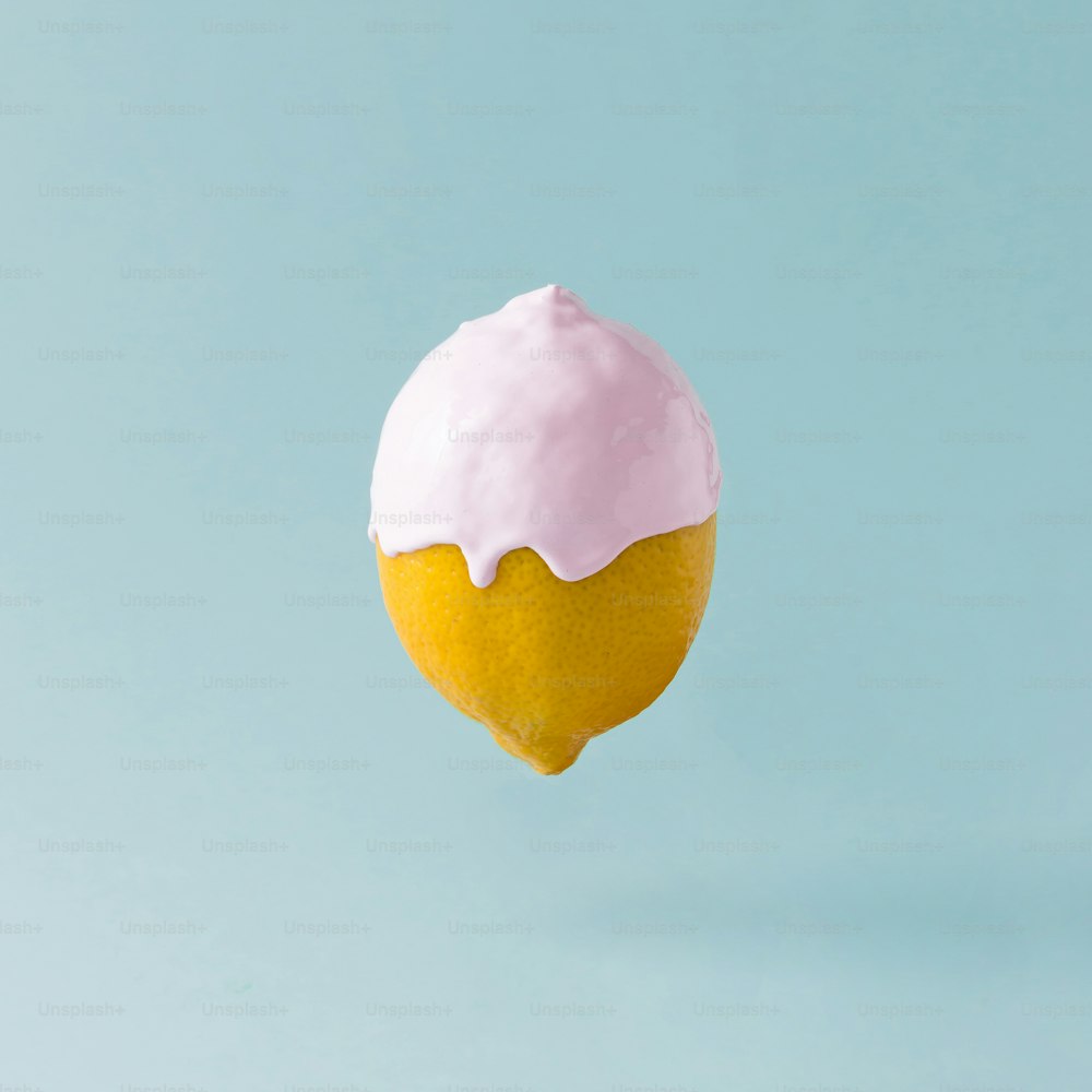 Lemon with ice cream topping on pastel blue background. Food creative concept.