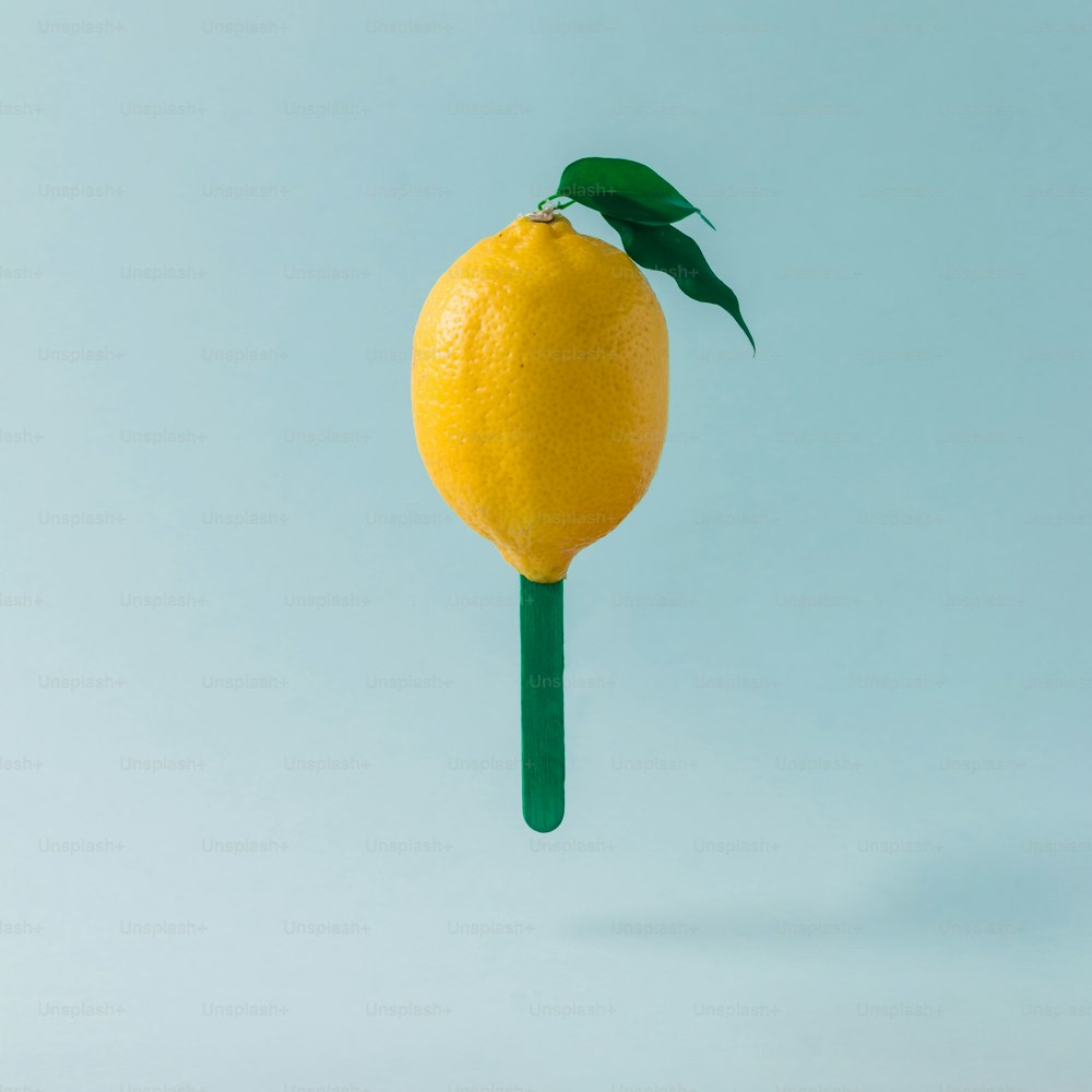 Zitrone mit Eisstange auf pastellblauem Hintergrund. Kreatives Food-Konzept.