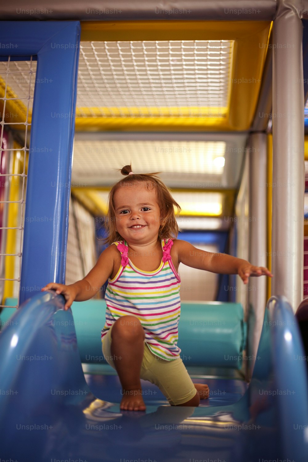 Little girl in playground. Happy little girl sitting on toboggan.