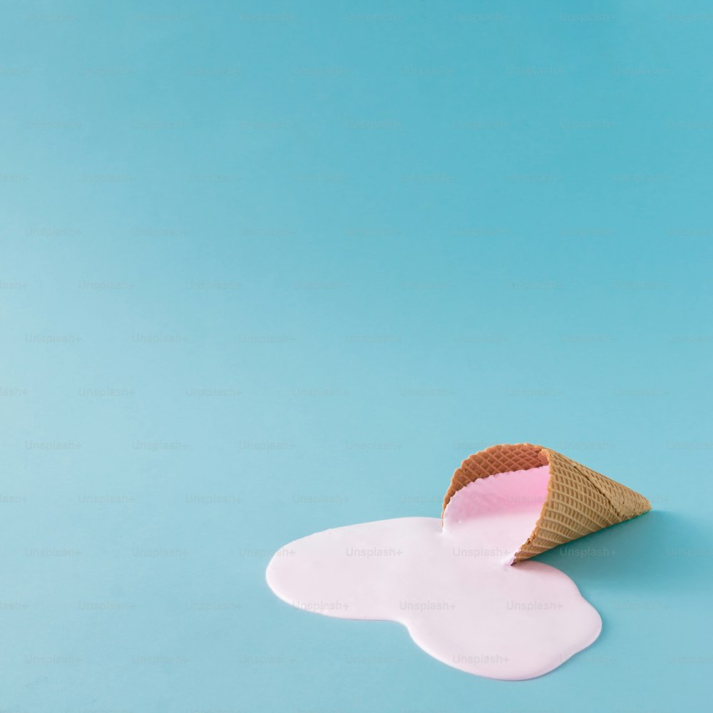 Pink ice cream spilled on pastel blue background. Minimalistic summer food concept.