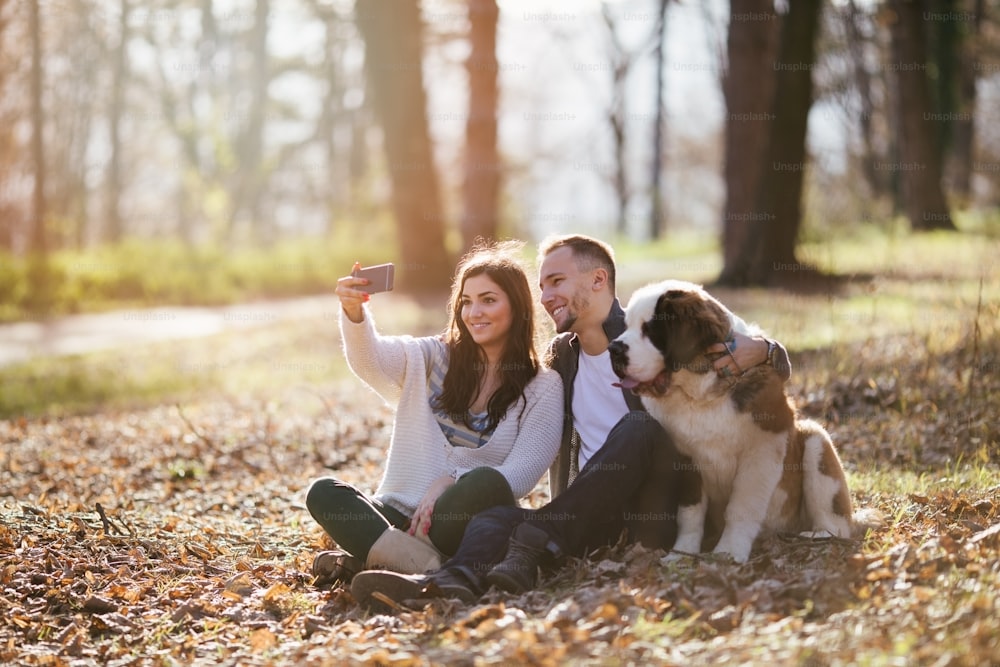Jovem casal desfrutando da natureza ao ar livre, juntamente com seu adorável filhote de São Bernardo. Tema de pessoas e cães.