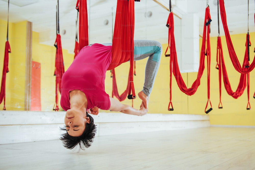 Young beautiful woman practicing yoga Fly with a hammock in the bright studio. The concept of mental and physical health and harmony