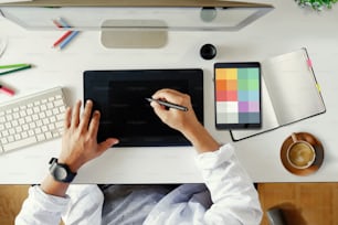 Stylish workspace with graphic designer working on computer using digital tablet at office.