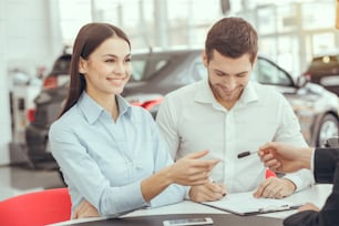 Hombre y mujer jóvenes en un contrato de arrendamiento de servicio de alquiler de automóviles