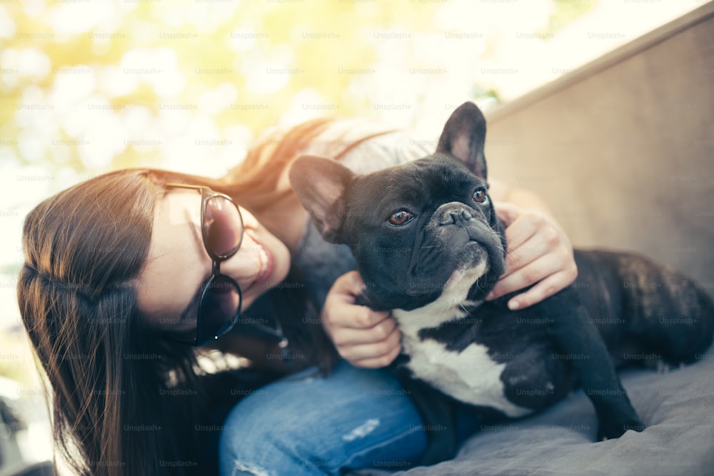 Beautiful teenage girl sitting in cafe restaurant with her adorable French bulldog puppy. People and dogs theme.