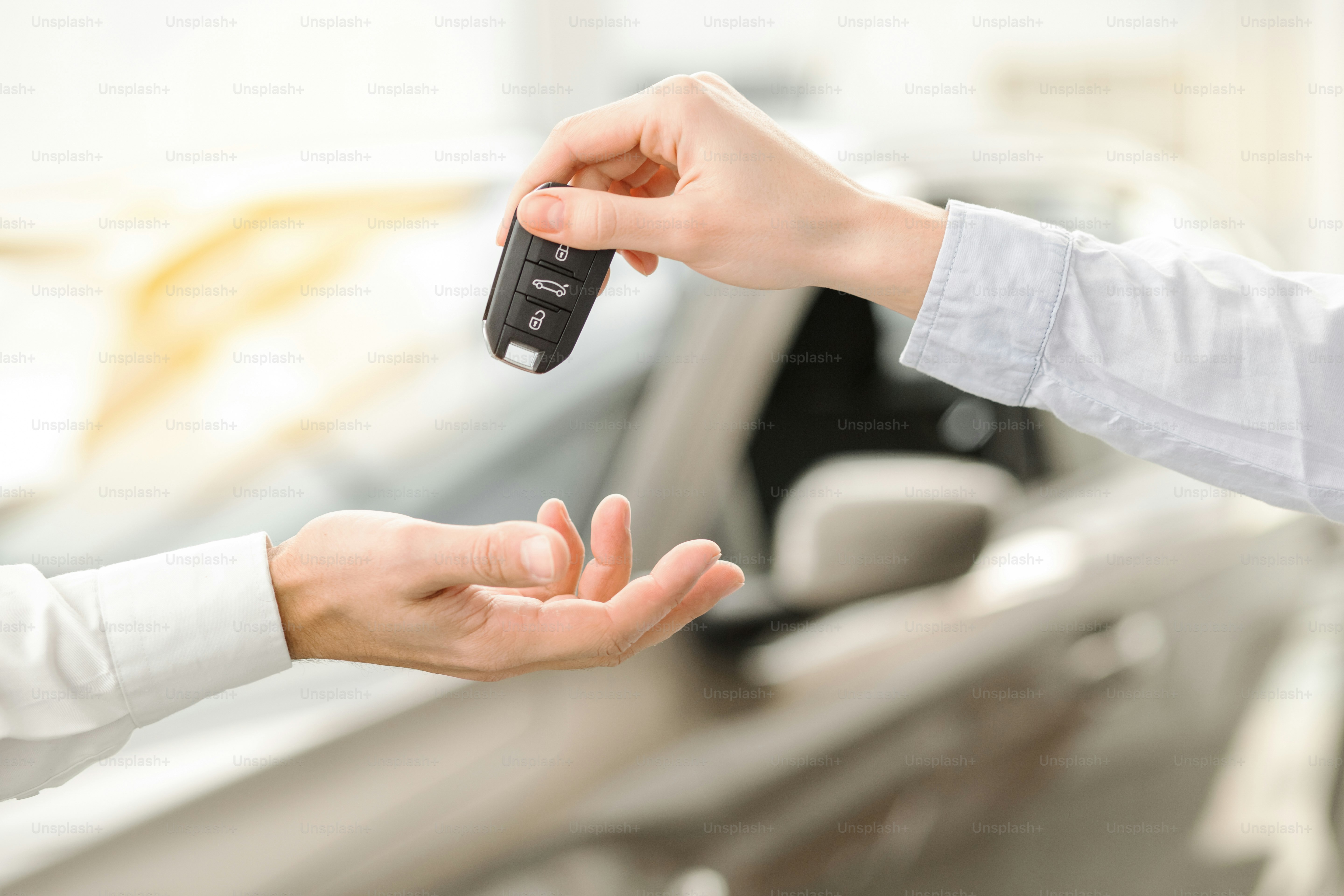 Young man standing near the car getting keys rental service