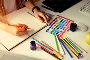 Jeune designer dessinant des croquis sur tablette graphique dans un bureau d’atelier.