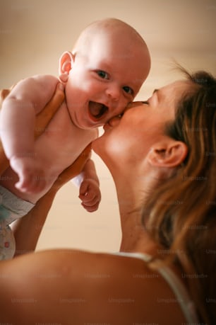 Young mother playing with her baby boy in bed. Mother enjoying in free time with her little cute baby.