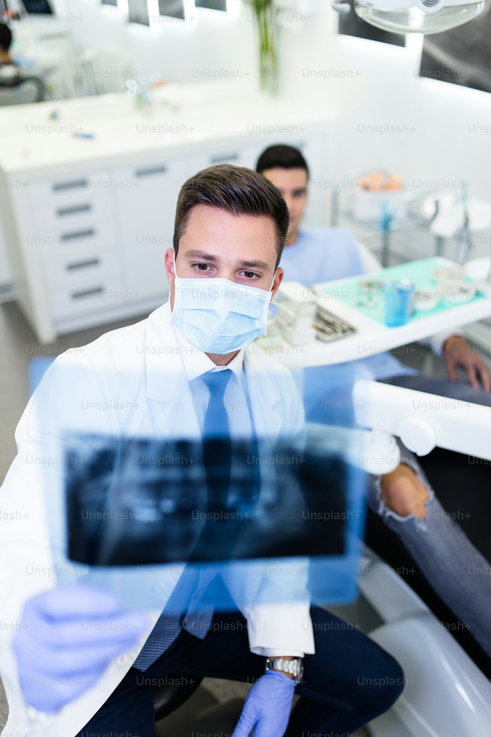 Handsome and attractive male dentist looking at dental x-ray.