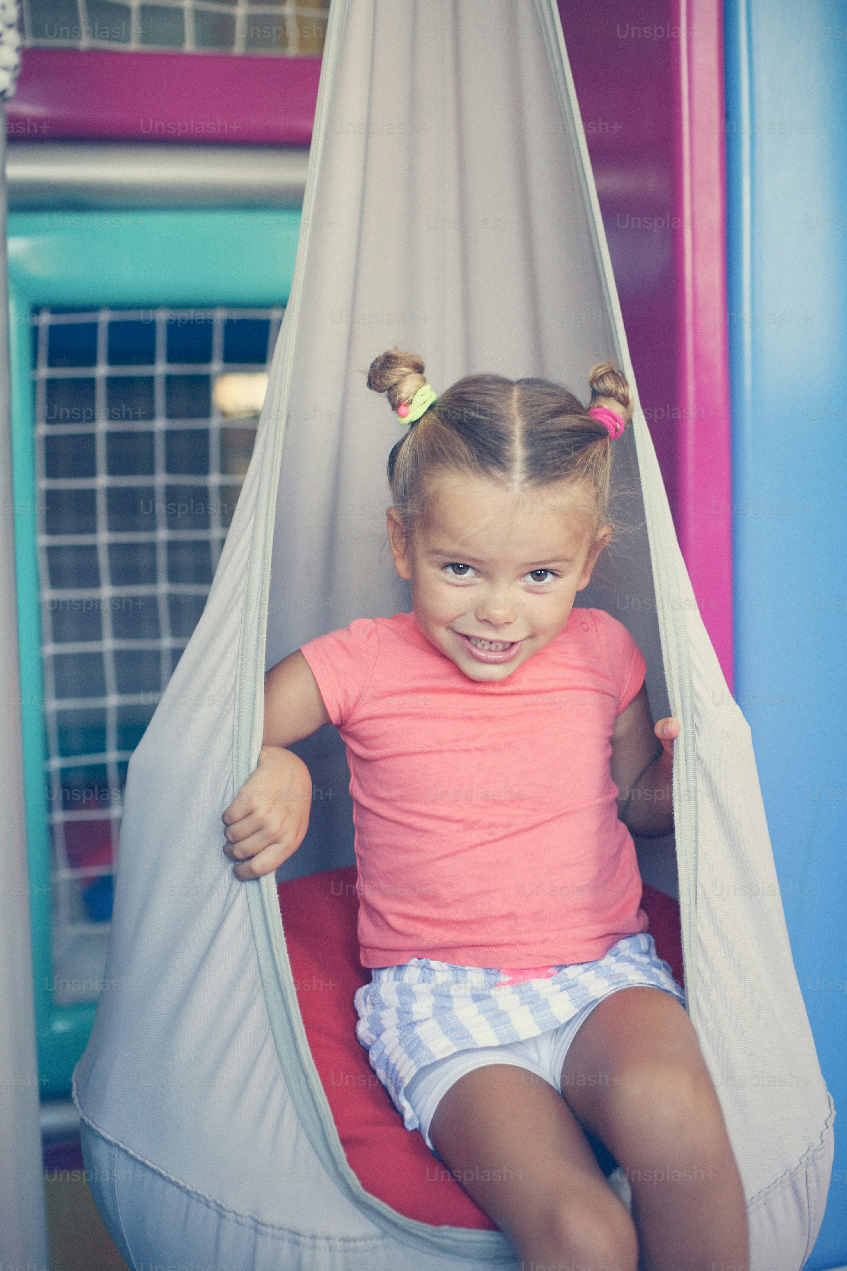 Little girl playing in playground.  Caucasian girl sitting on the swing. Looking at camera.