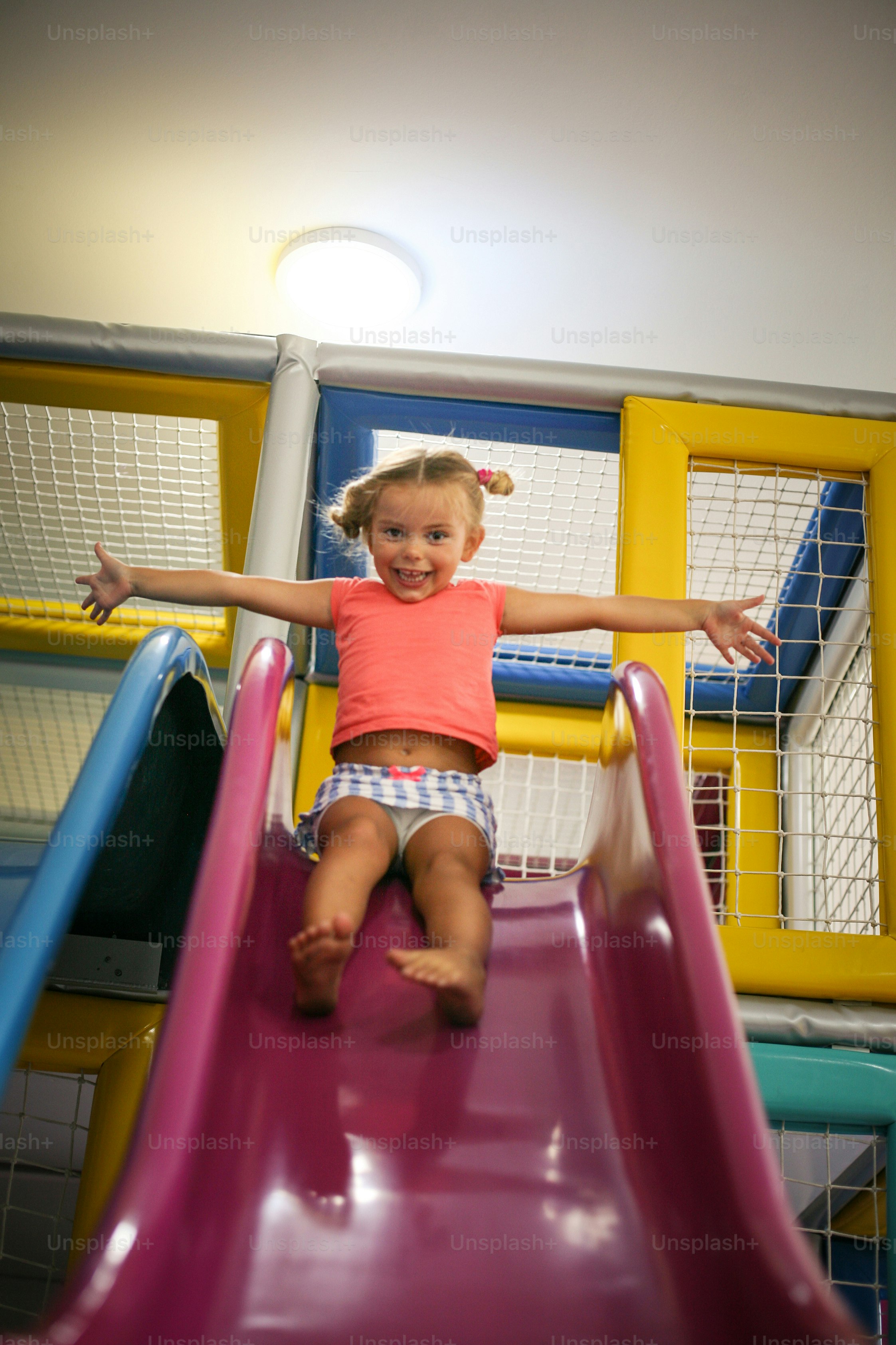Parque infantil de alfileres para niñas. Chica caucásica deslizándose en tobogán.