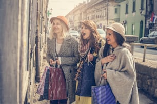 Três meninas em pé na frente da boutique e olhando roupas." n