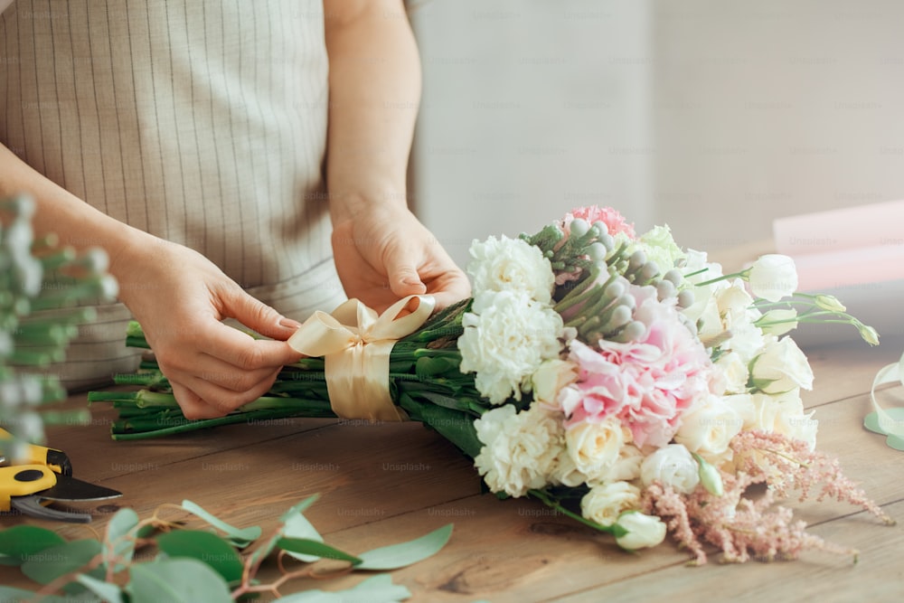 Young female florist working with flowers making bouquet