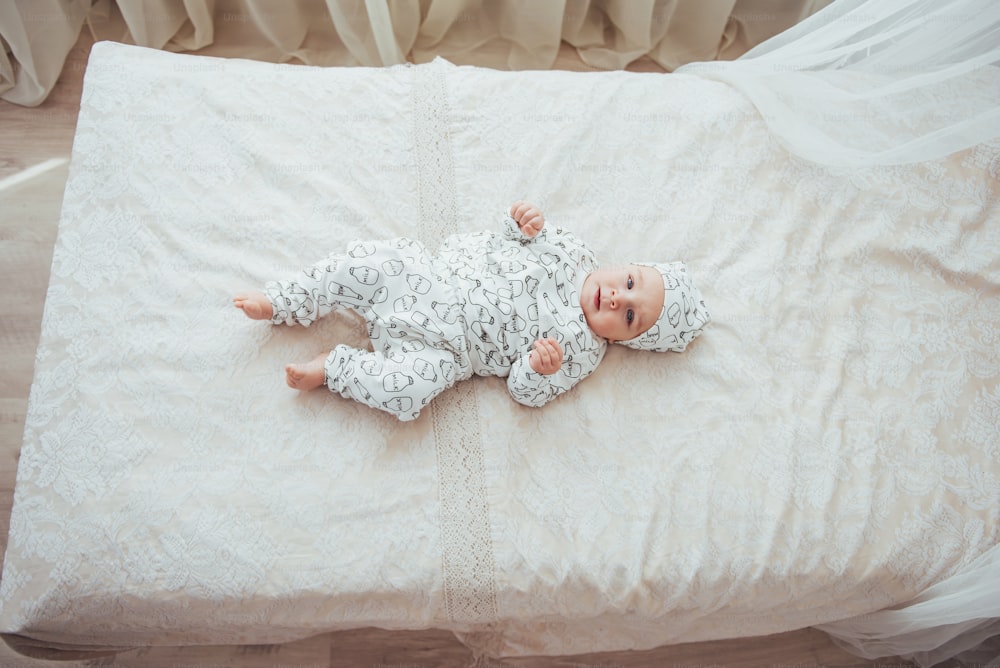 Newborn baby dressed in a suit on a soft bed in the studio