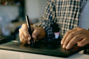 Mão de designer masculino trabalhando em sua mesa usando caneta e tablet gráfico digital.