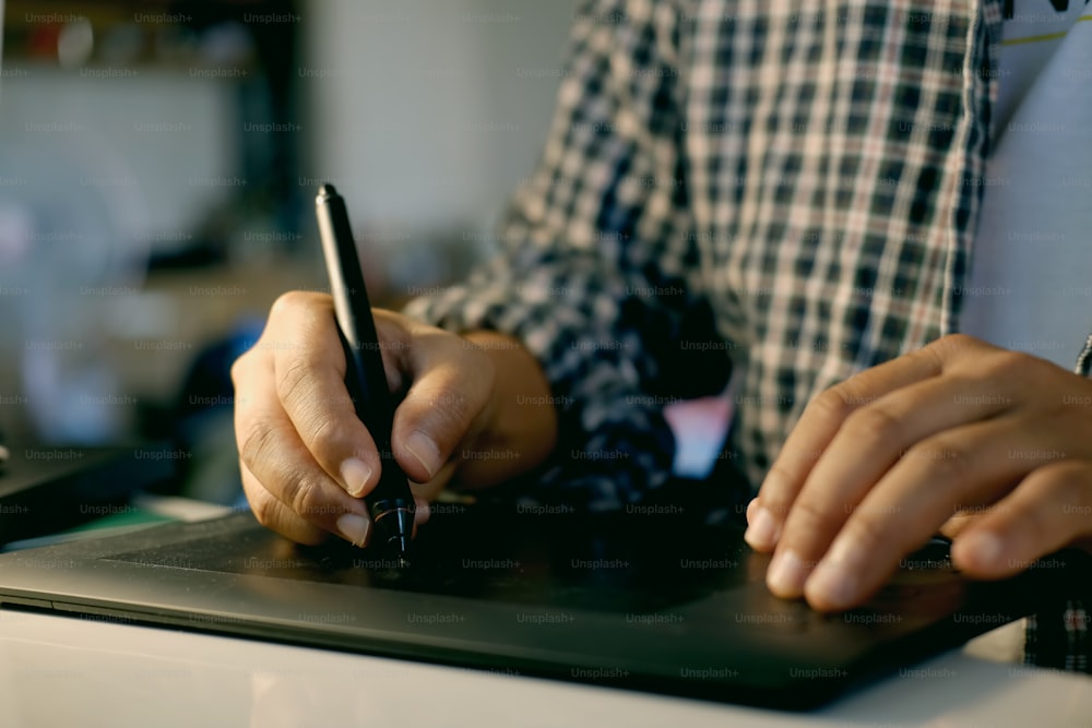 Hand of male designer working at his desk using stylus and digital graphics tablet.