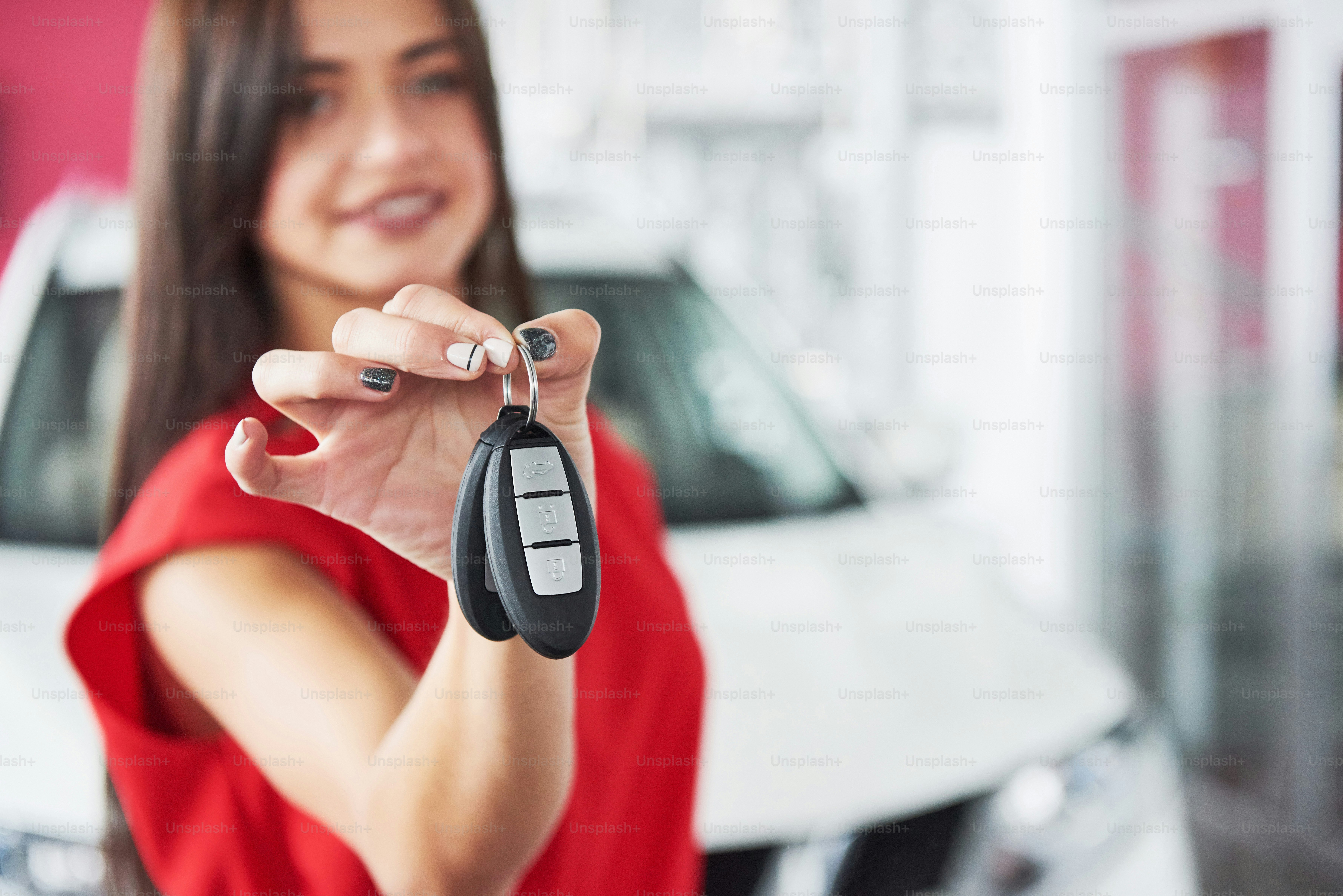 Smiling car salesman handing over your new car keys, dealership and sales concept. Happy girl the buyer.