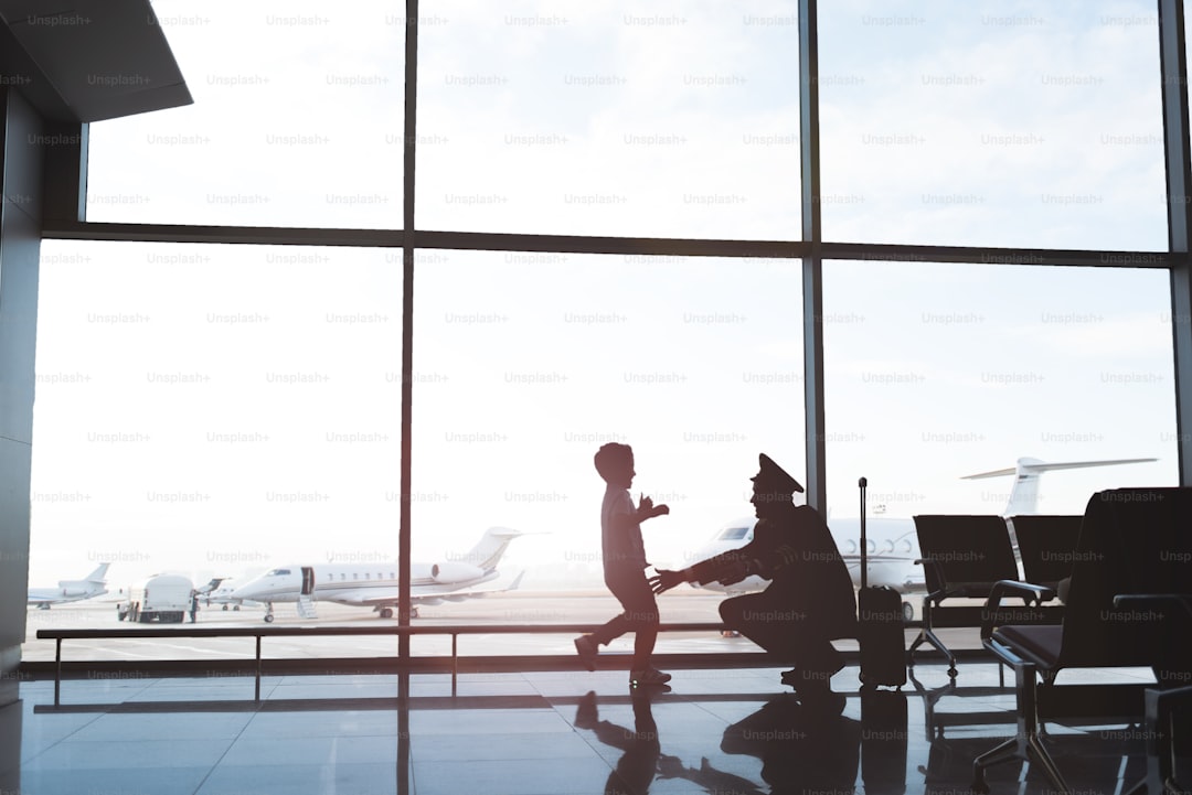 Happiest reunification. Son running to embrace of father pilot, who squatting and going to hug child. Copy space on left