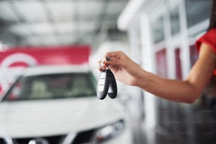 Smiling car salesman handing over your new car keys, dealership and sales concept. Happy girl the buyer.