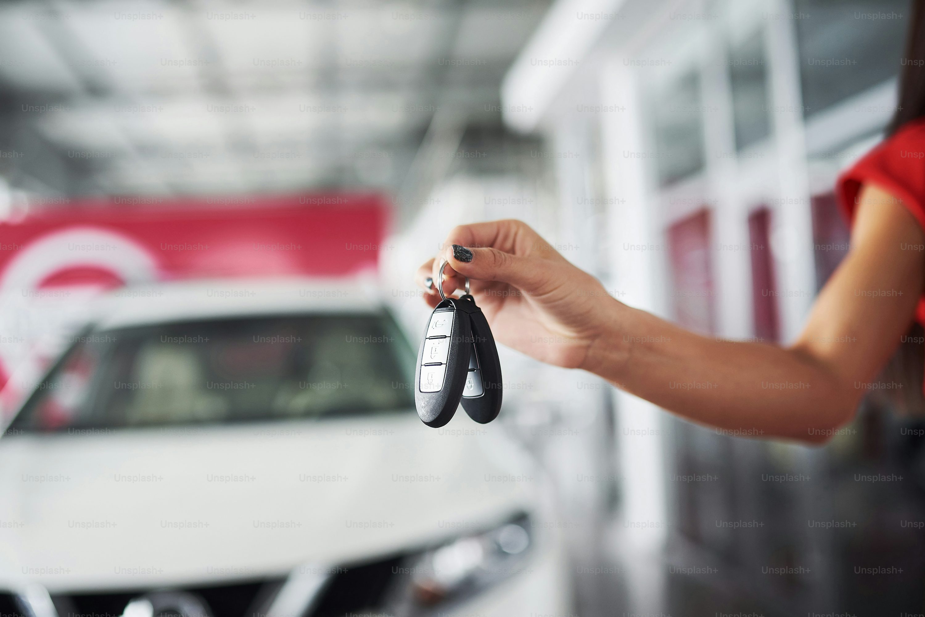 Smiling car salesman handing over your new car keys, dealership and sales concept. Happy girl the buyer.