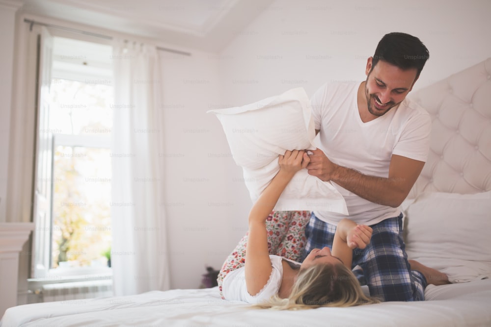 Beautiful couple pillow fighting and smiling