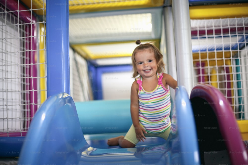 Little girl in playground. Happy little girl sitting on toboggan.