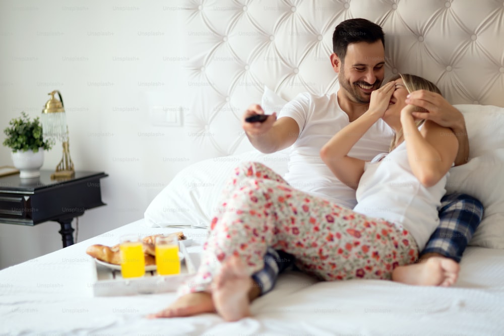 Couple relaxing in pajamas and watching tv in bed