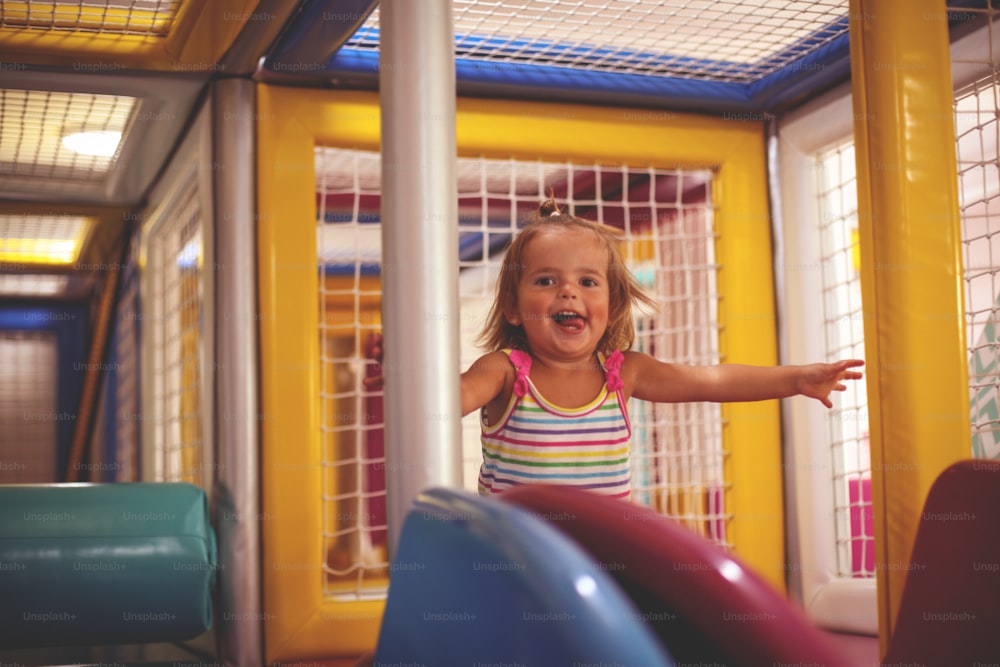 Kleines Mädchen auf dem Spielplatz. Glückliches kleines Mädchen auf dem Schlitten.